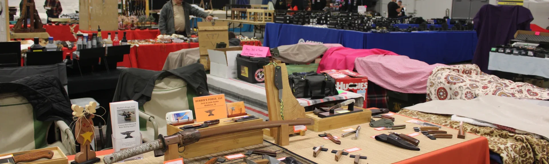 Vendor booths with knives, holsters and outdoor gear at a gun show